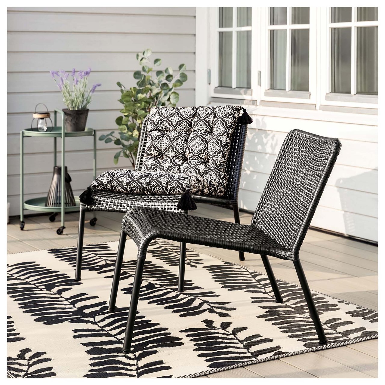 Terrasse mit schwarzen Relaxstühlen mit schwarz-weiß gemustertem Kissen.