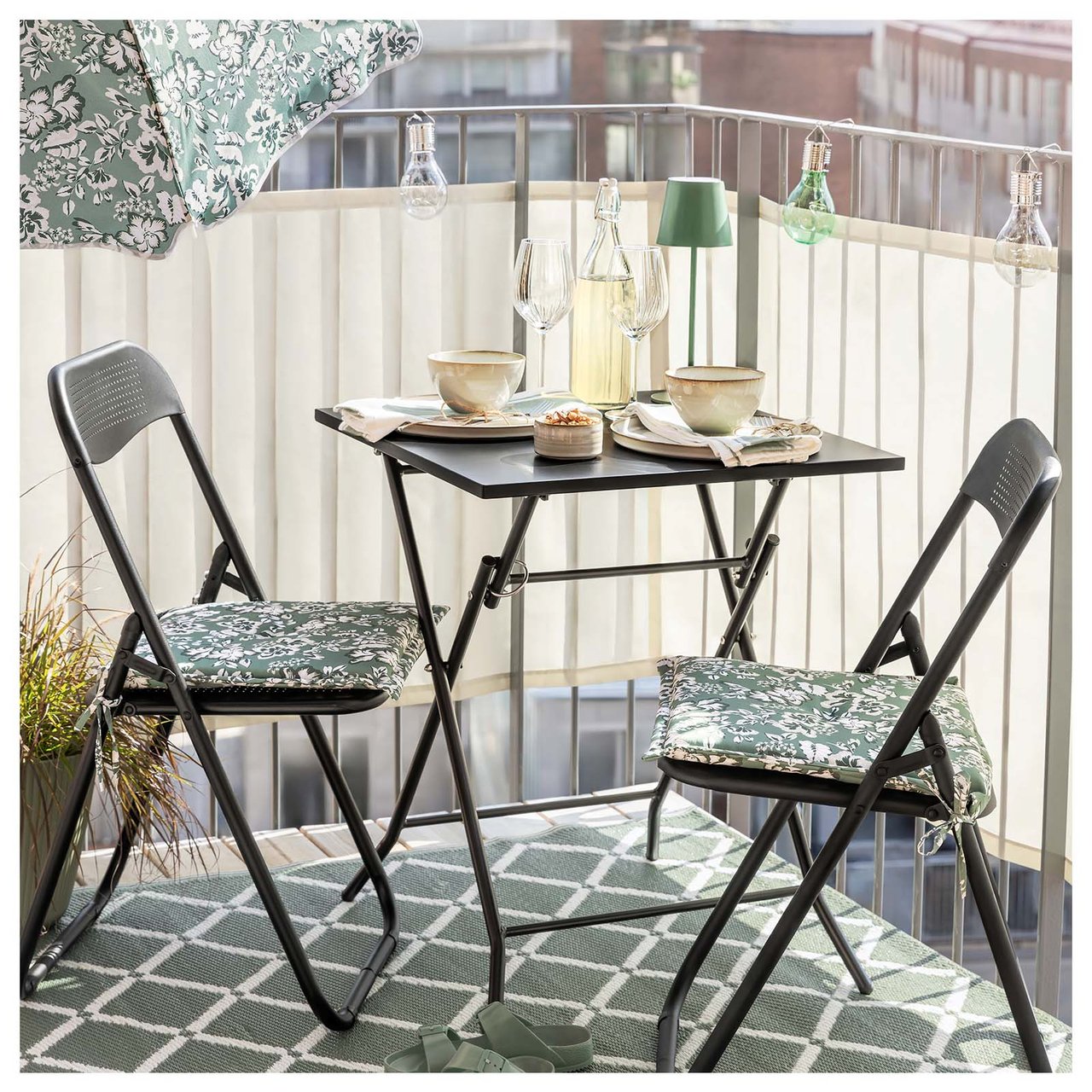 Balkonmöbel aus schwarzem Stahl auf dem Balkon mit Sonnenschirm und kariertem, grünem Bastteppich