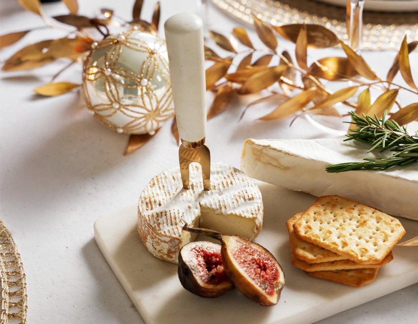 Nærbilde av ostefat med kjeks, frukt og dekorasjon.