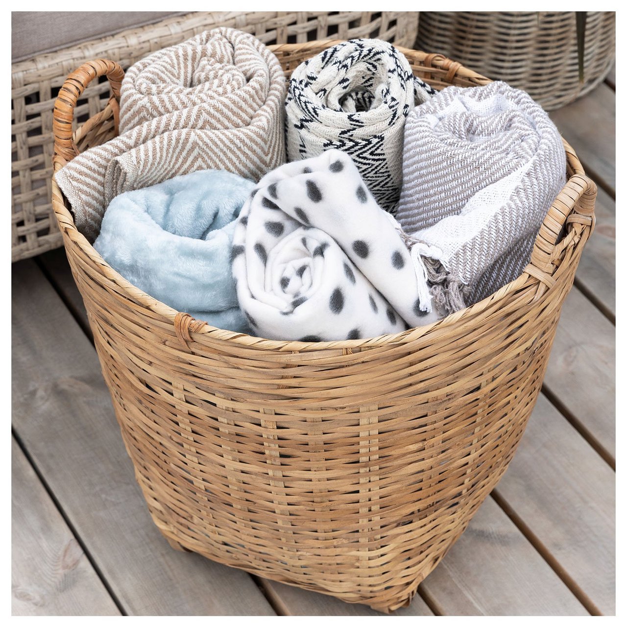 Ihoprullade filtar i en korg bredvid en fåtölj.