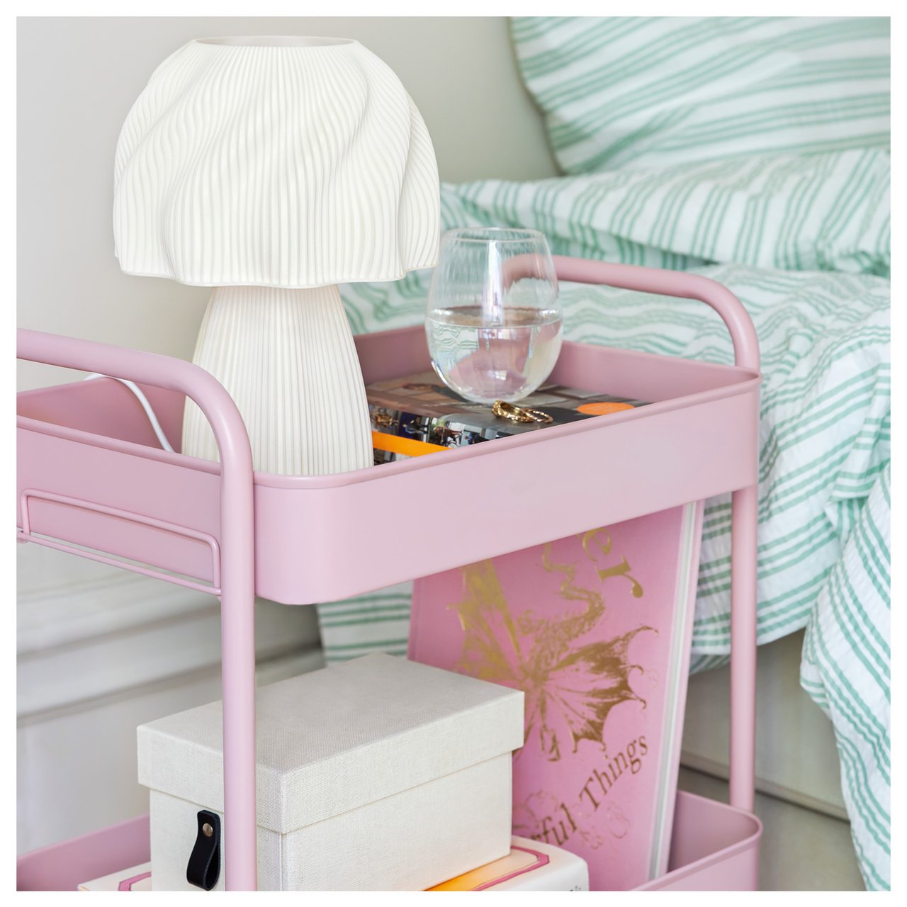 Rosa tralle som fungerer som nattbord i et soverom med pastellinteriør.