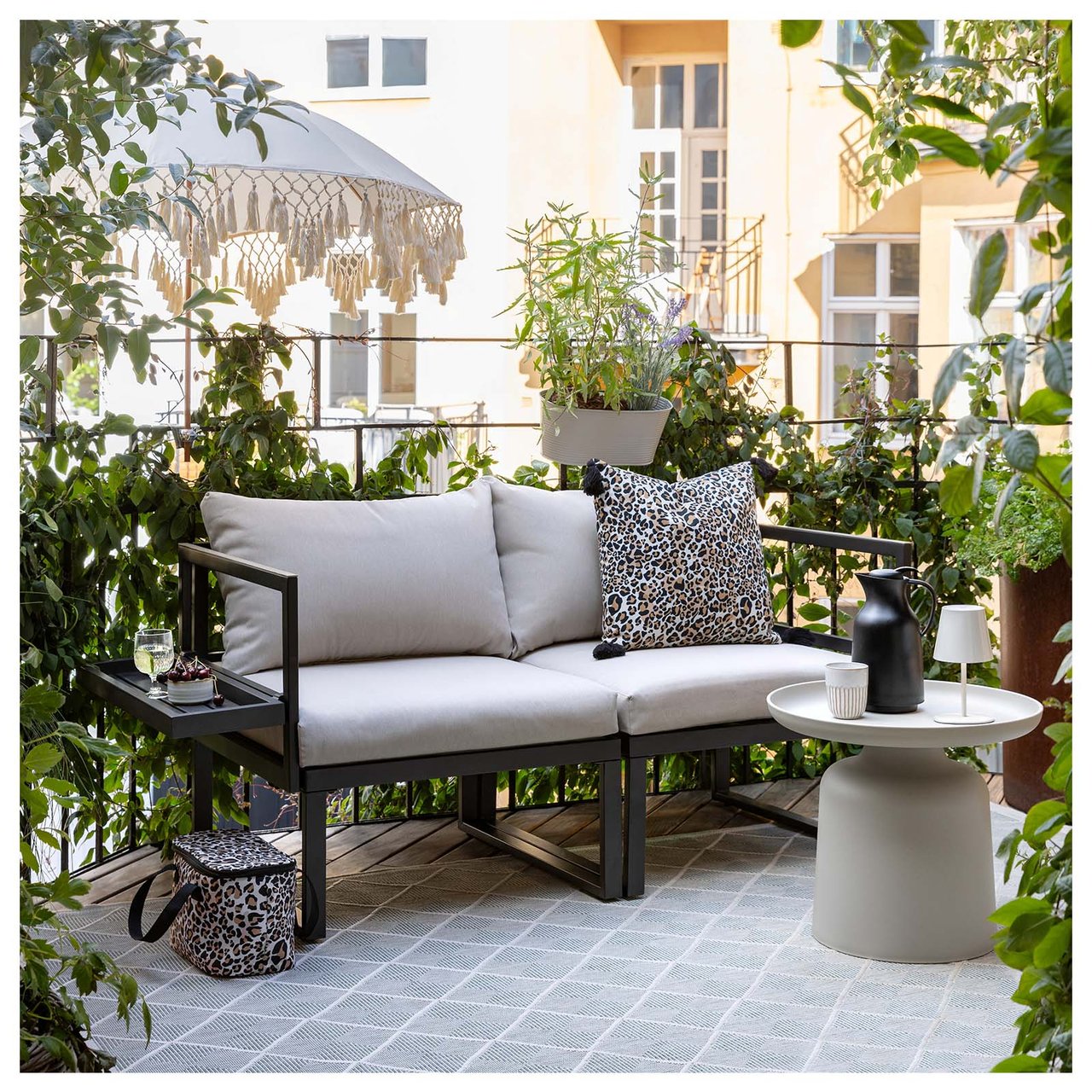 En toseters sofa i svart stål med beige puter står på en balkong.