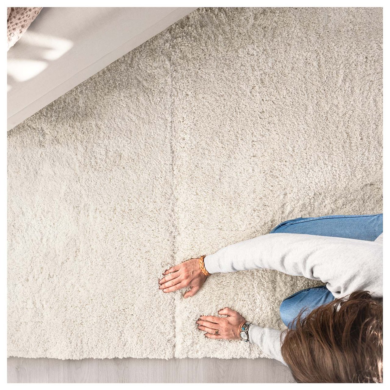 Hände legen zwei weiße Teppiche der gleichen Art zusammen.