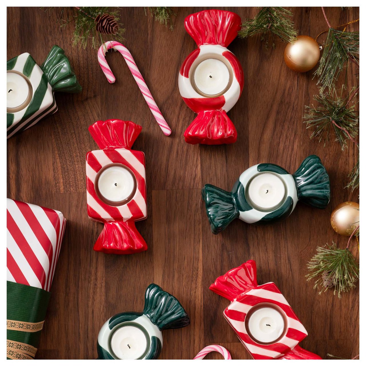 Karkin muotoiset kynttilänjalat aseteltuna pöydälle yhdessä joulukarkkien ja pakettien kanssa.