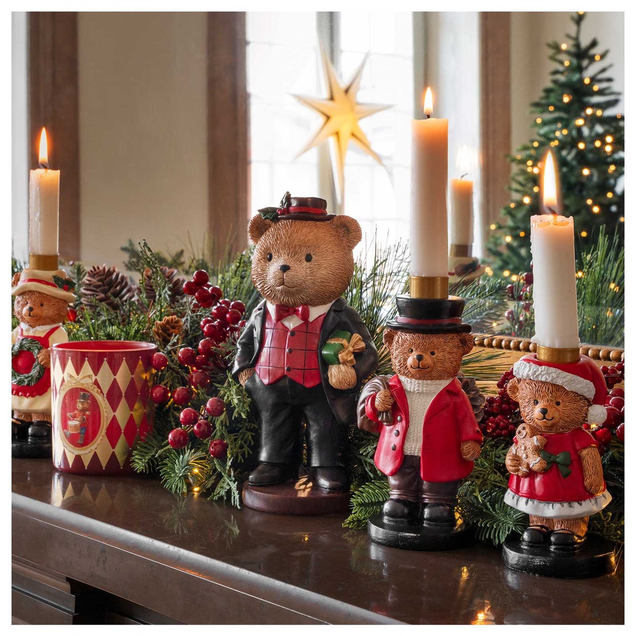 Ljusstakar i form av julklädda björnar står på en spiselkrans. I spegeln bakom syns en julgran och en adventsstjärna.