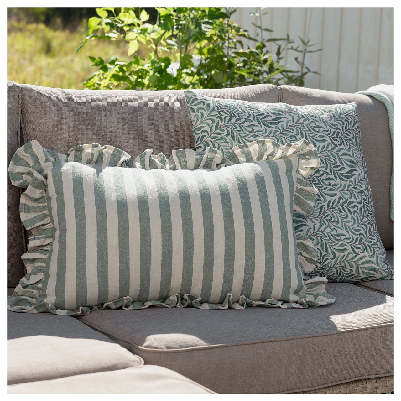 Gröna kuddar i en beige utomhussoffa.