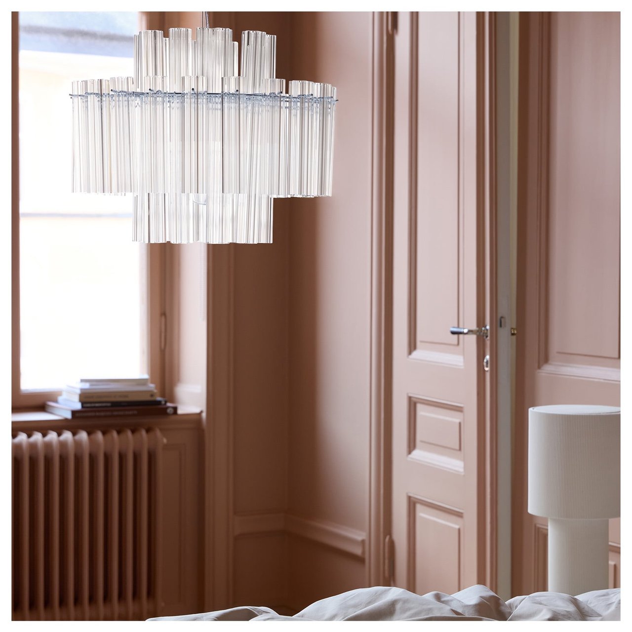 Taklampa i glas och beige golvlampa i ett sovrum.