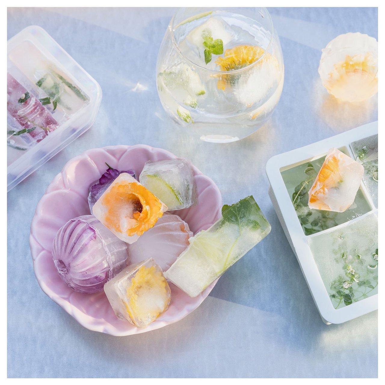 Iskuber med ätbara blommor i ligger i en skål och i ett glas.