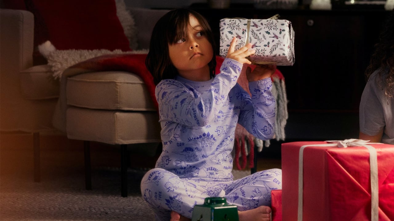 Pojke i pyjamas håller upp en julklapp.