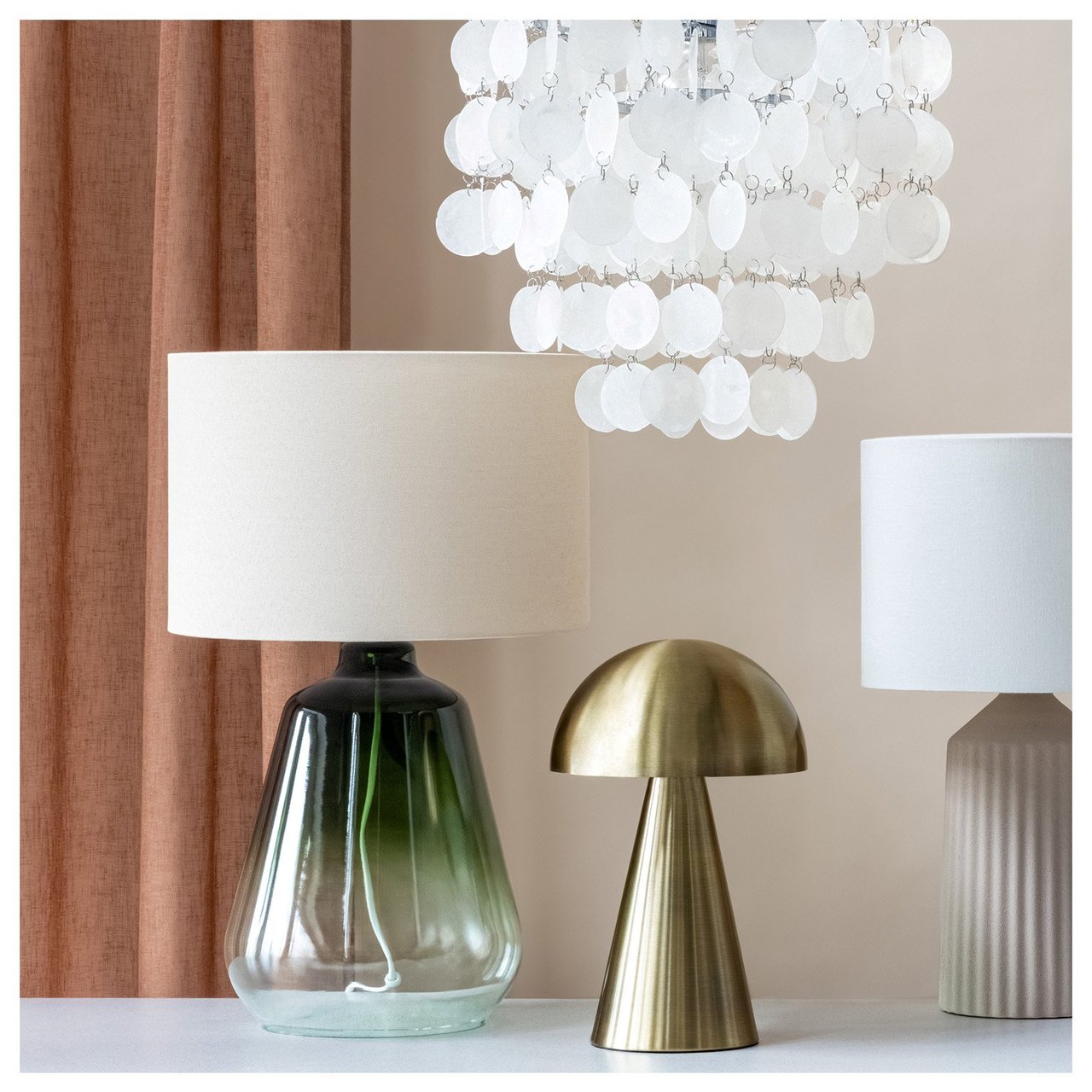 Lampen in verschiedenen Materialien und Designs hängen und stehen auf/über einer Anrichte.