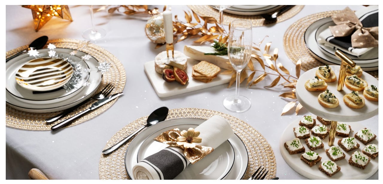 Dukat bord med snittar, ostbricka och dekorationer för en festlig måltid.