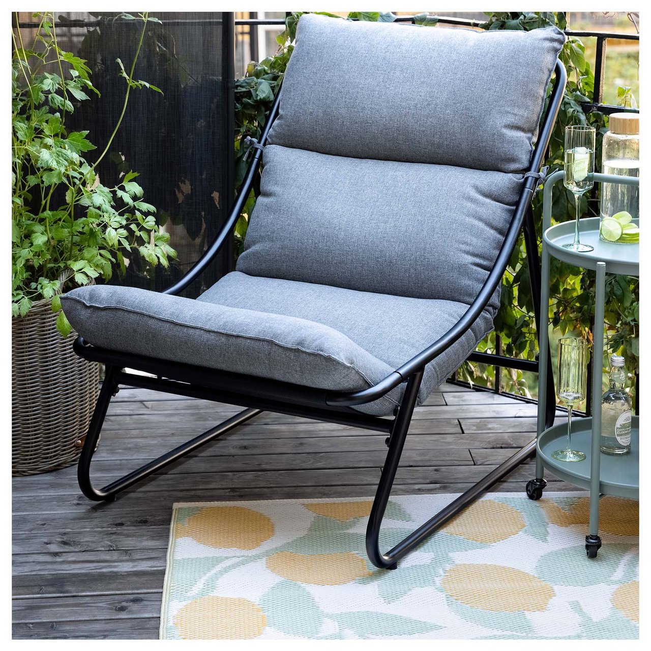 Loungelenestol i svart og grått på et teppe med sitronmønster.¬lenestol i svart og grått på en matte med sitronmønster.