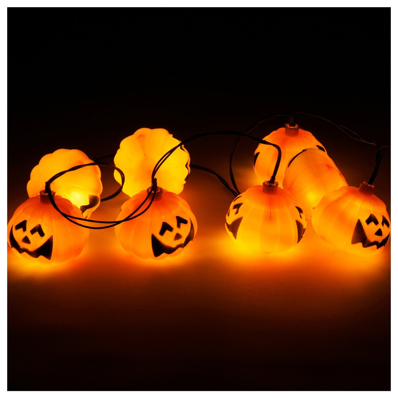 Lysslynge i form av flere små halloween-gresskar lyser i mørkt miljø.