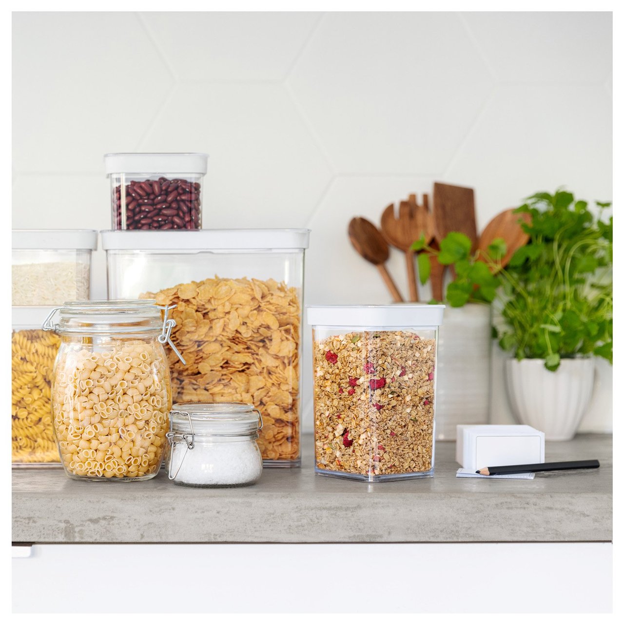 Küchentheke mit Vorratsbehältern aus Glas und Kunststoff, gefüllt mit Cornflakes, Müsli und Nudeln.