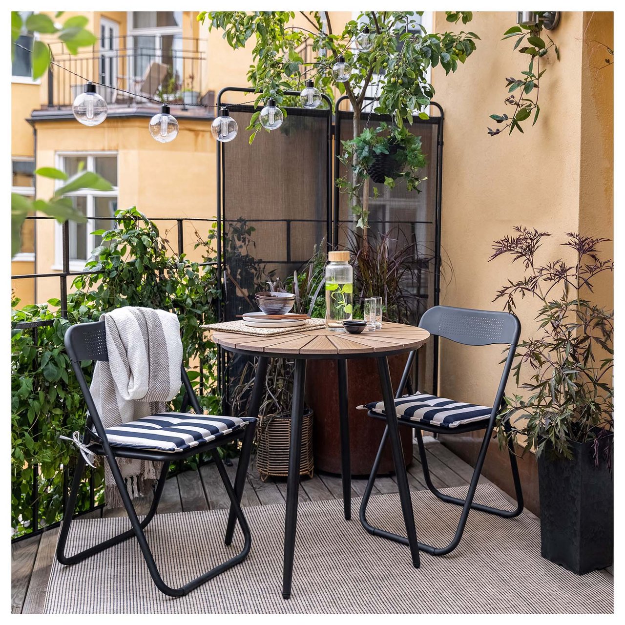 Balkon mit schwarzen Stühlen mit schwarz-weiß gestreiften Sitzkissen.