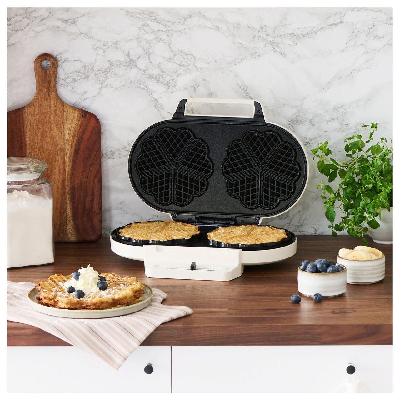 Auf der Küchenarbeitsfläche steht ein Doppel-Waffeleisen mit zwei frisch gebackenen Waffeln.