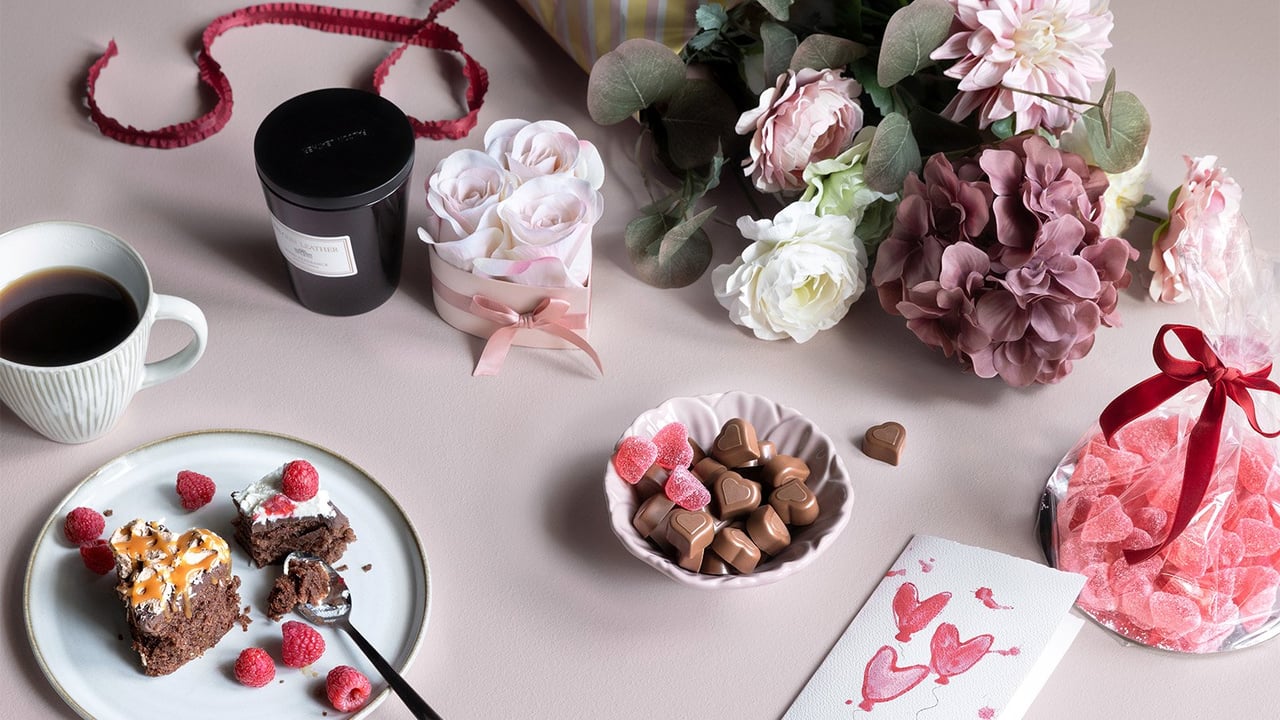 Alla hjärtans dag-presenter: blombukett, chokladtårta, hjärtgodis, kaffe och kort med hjärtan.