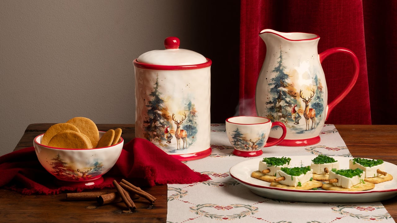 Kopper og serveringsskåler er satt frem med småkaker og snitter på et julepyntet bord.