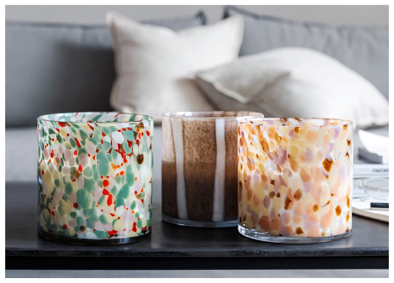 Drei dekorative Glaslampen stehen auf einem Tisch vor Sofakissen in häuslicher Umgebung.