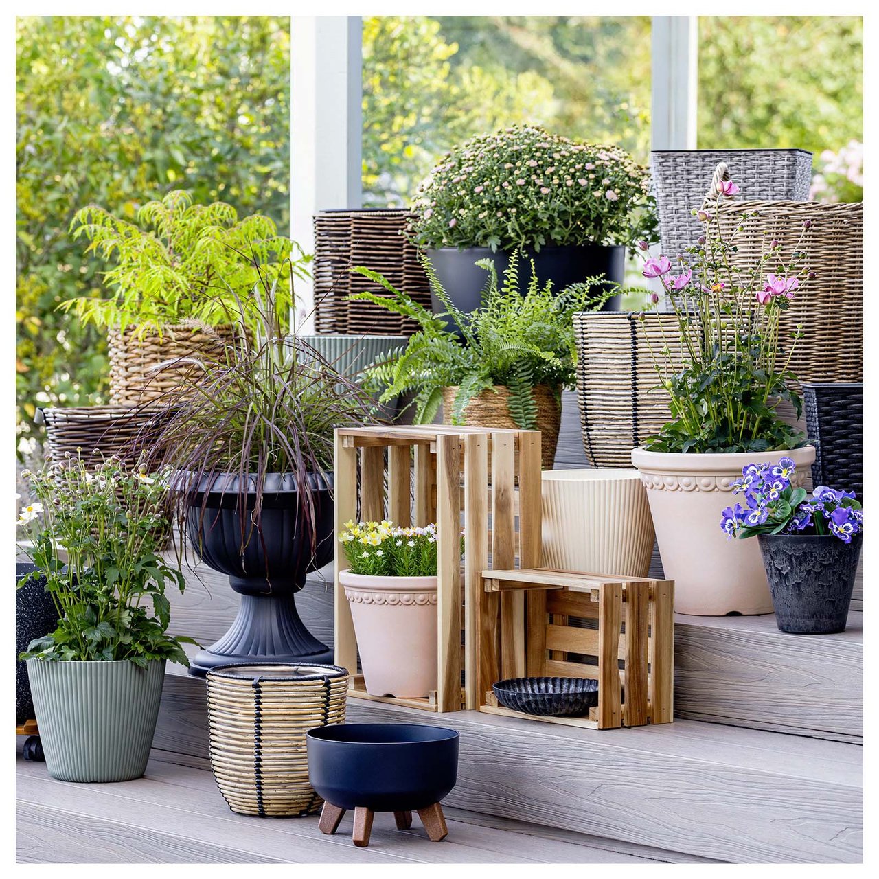 Viele verschiedene Arten von Töpfen gestapelt auf einigen Treppenstufen, die zu einer verglasten Terrasse führen.
