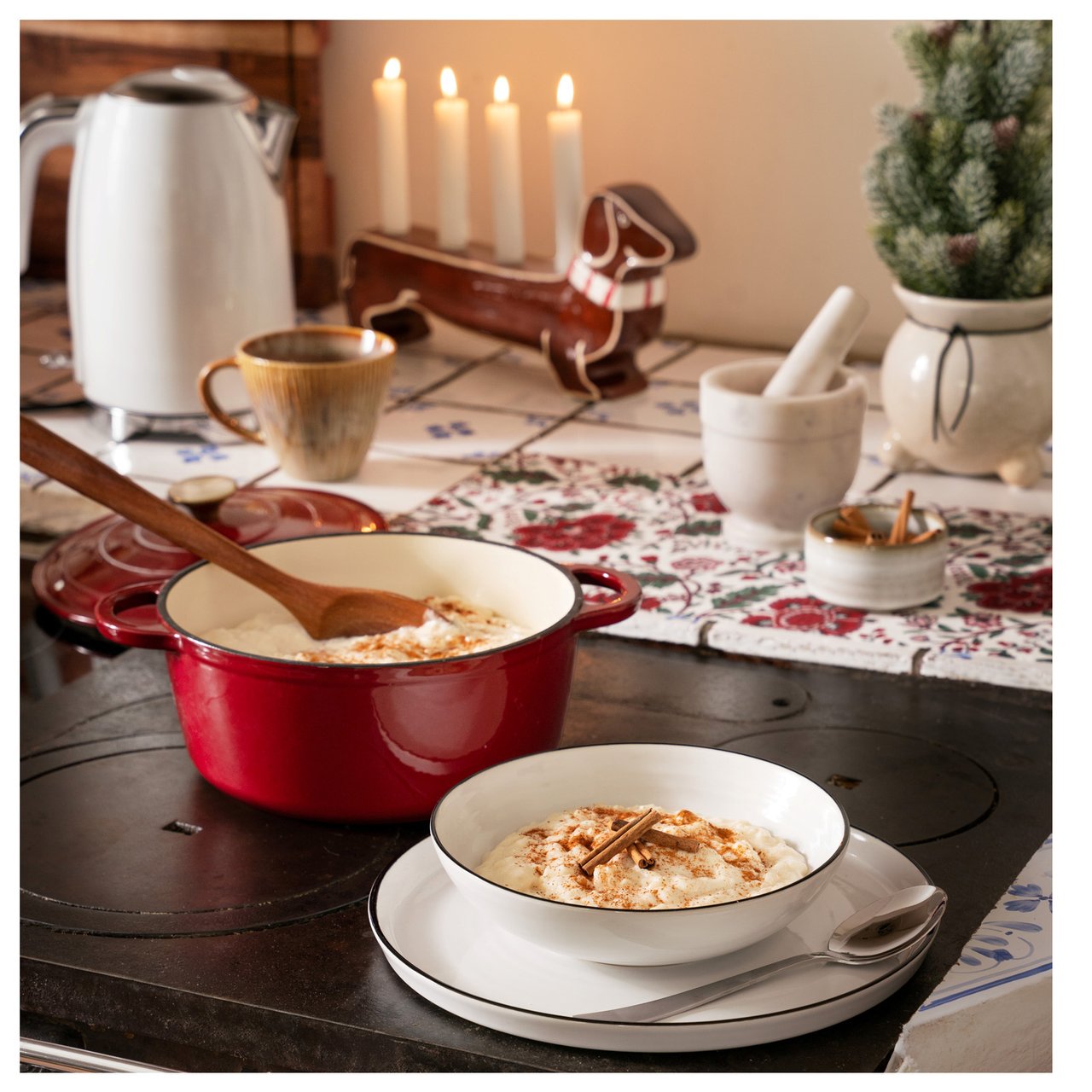 Roter Topf und Teller Milchreis auf altem Holzofen.