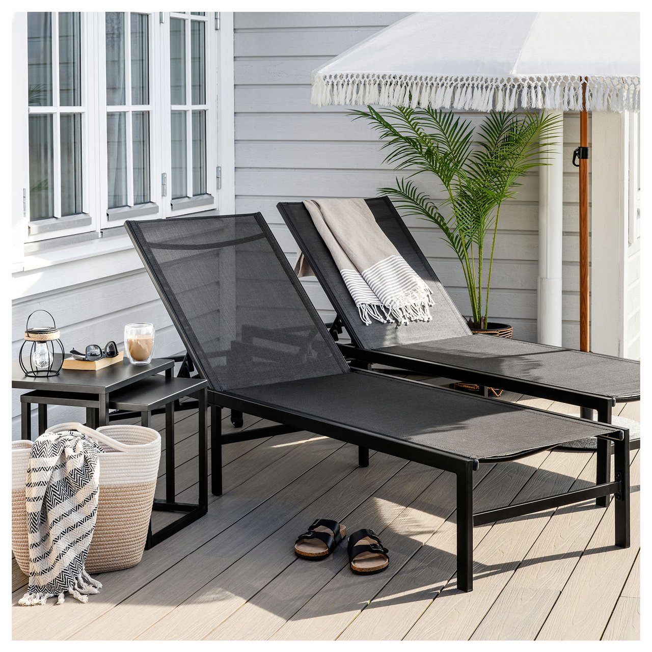 Eine Sonnenliege, ein Campingstuhl und zwei Liegestühle stehen an einem Pool, der von Sonnenschirmen und Bäumen umgeben ist.