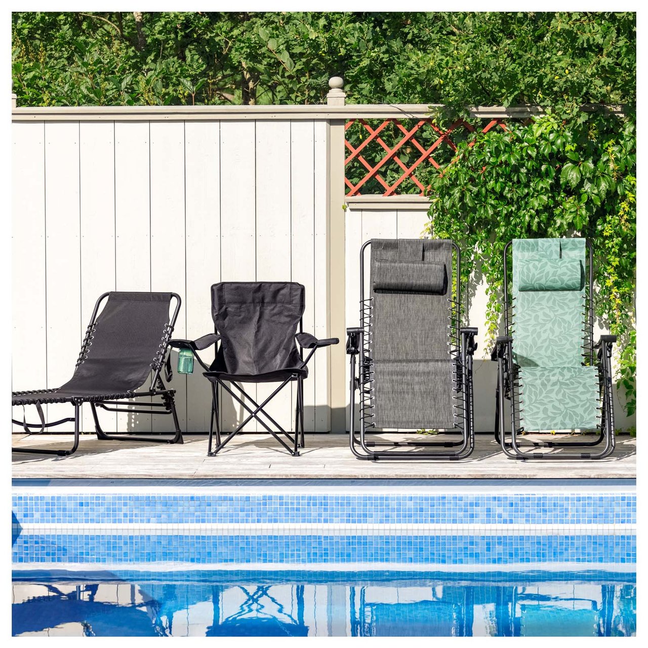 Eine Sonnenliege, ein Campingstuhl und zwei Liegestühle stehen an einem Pool, der von Sonnenschirmen und Bäumen umgeben ist.