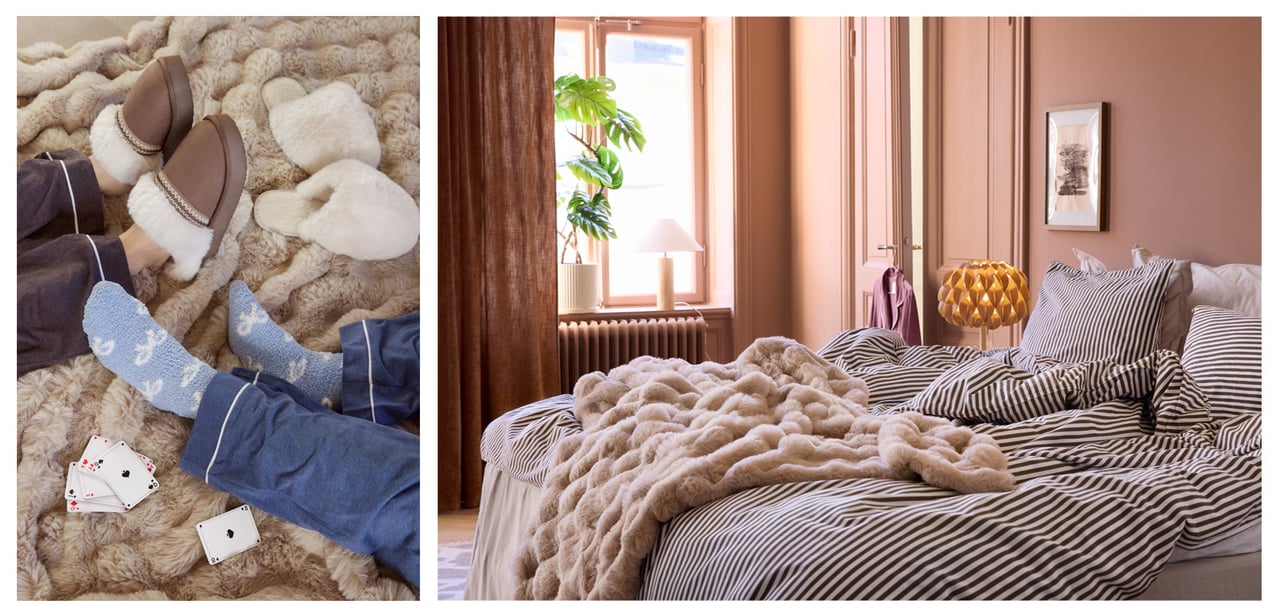 Füße mit Socken und Hausschuhen auf einer flauschigen Decke. Eine Decke liegt auf einem Bett mit gestreifter Bettwäsche.