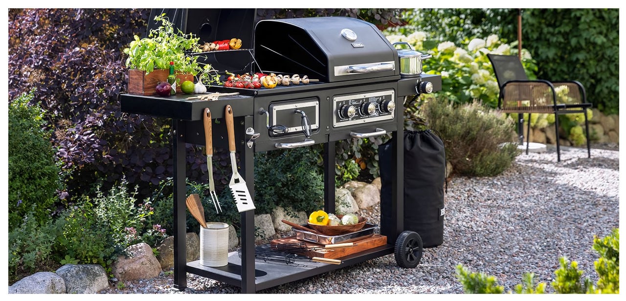 Kombinierter Kohle- und Gasgrill auf einem Kiesweg im Garten.
