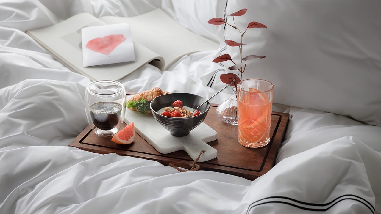 Frühstück im Bett mit Joghurt, Kaffee, Saft und einer Glückwunschkarte.