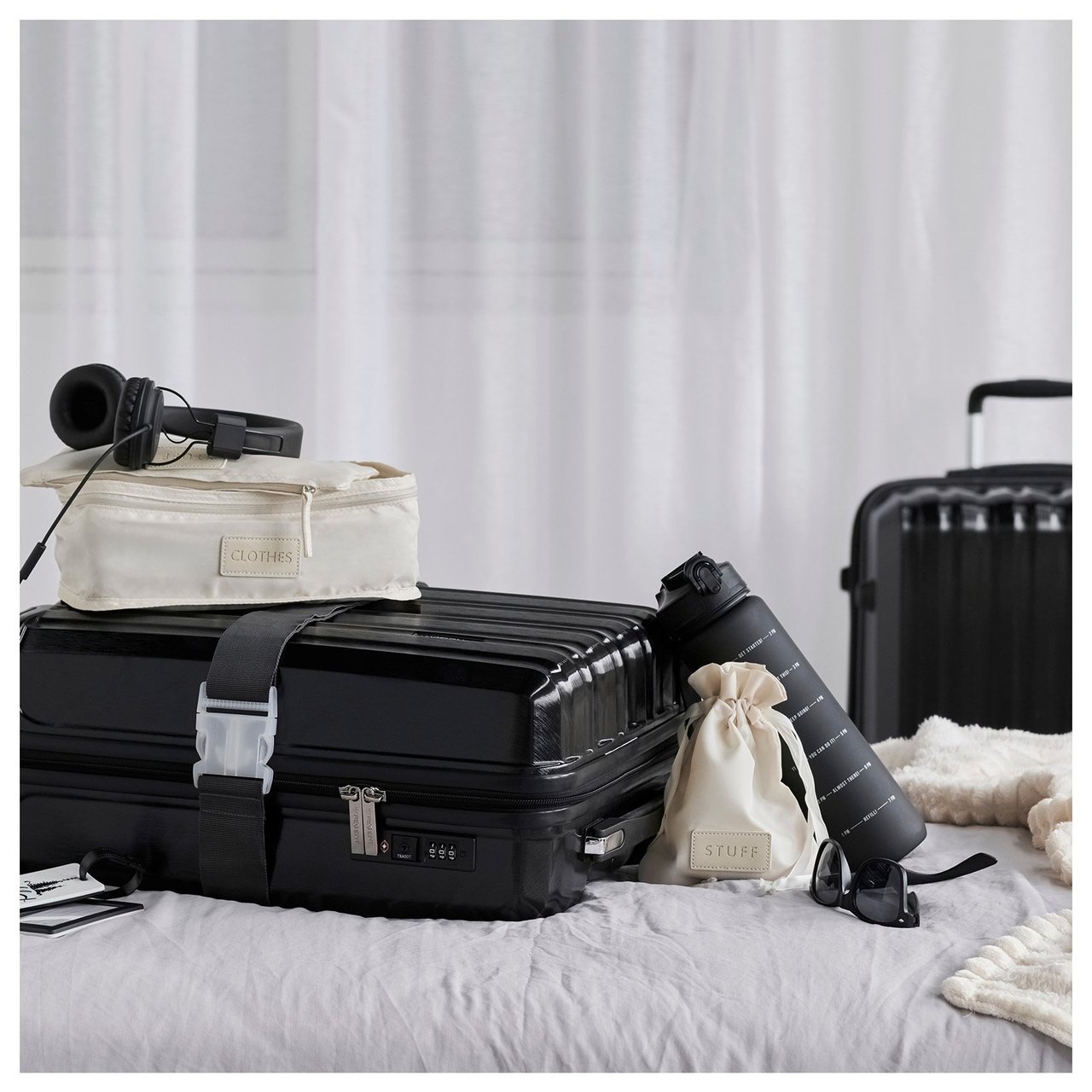 Kleiner gepackte Tasche und Nackenkissen auf einem Bett mit Koffer, im Hintergrund ein Schlafzimmer.