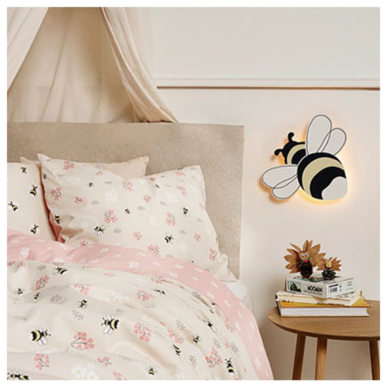 Kinderbett mit Bettwäsche mit Hummelmotiv und Lampe in Form einer Hummel.