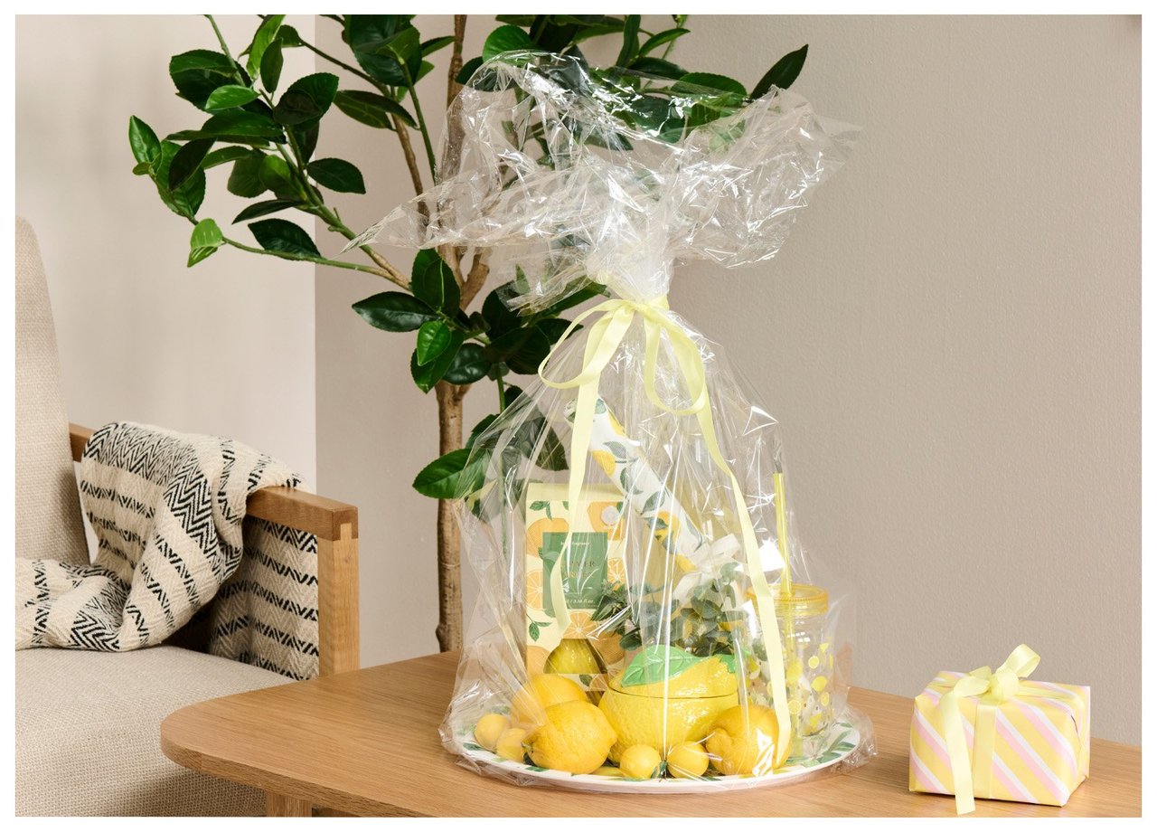 Keltaiset sitruunakuosiset sisustustuotteet sitruunakuosisella tarjottimella, käärittynä sellofaaniin. Vieressä on paketoitu lahja.