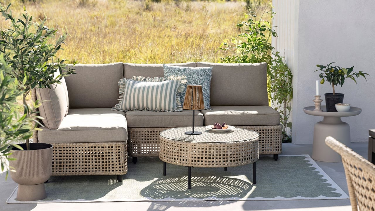 Terrasse mit beigefarbener Loungegruppe und passendem Tisch.