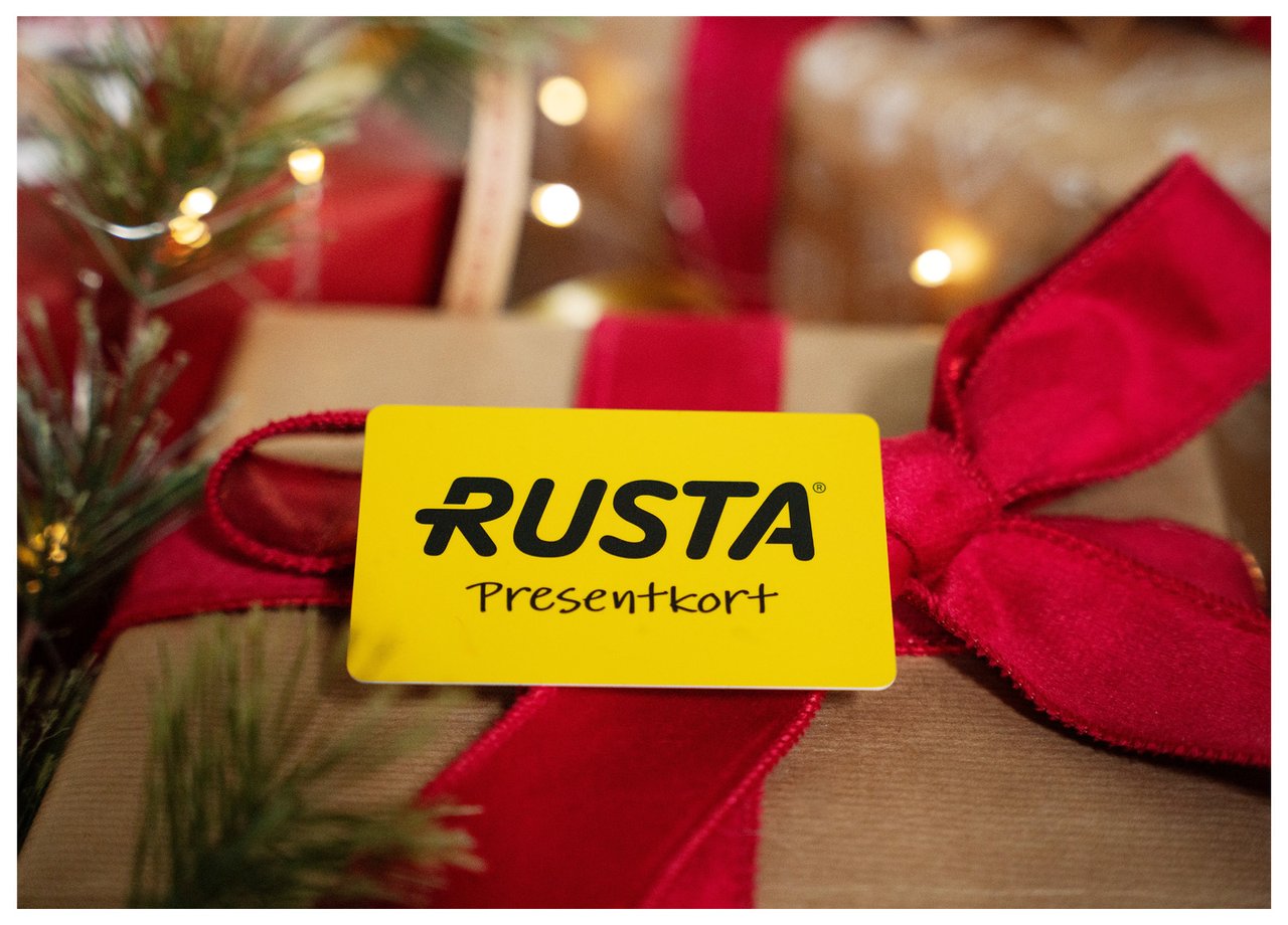 Julklapp inslagen med röda presentband och ett gult presentkort från Rusta.