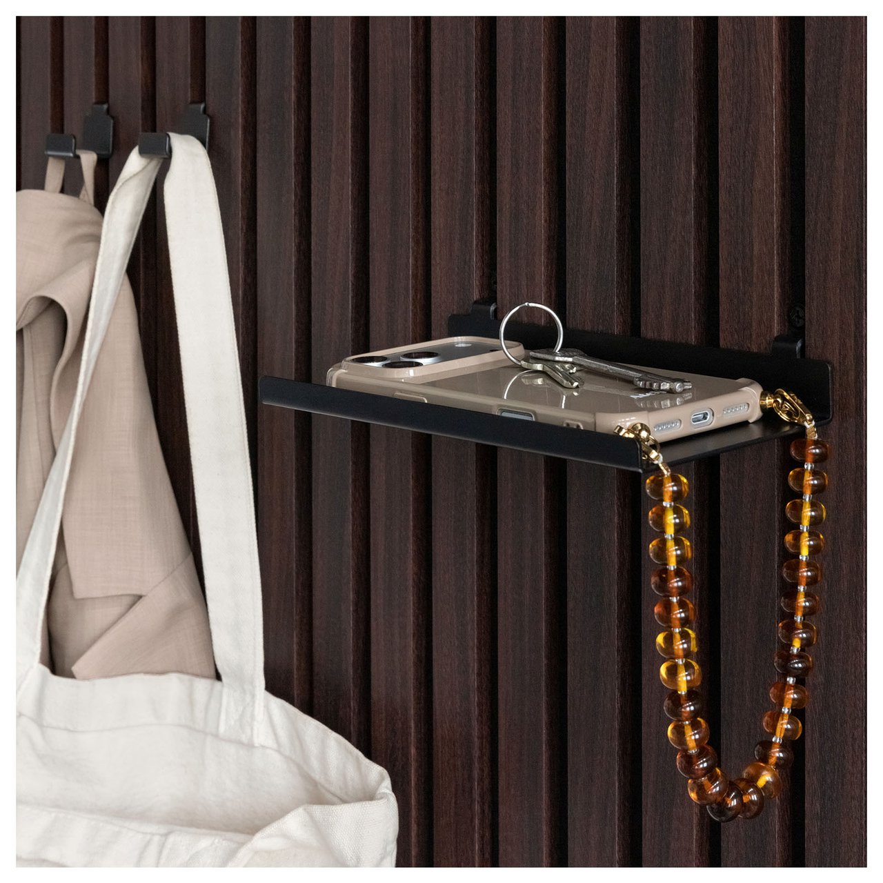 En mobiltelefon ligger på en liten hylla som monterats på mörk akustikpanel.