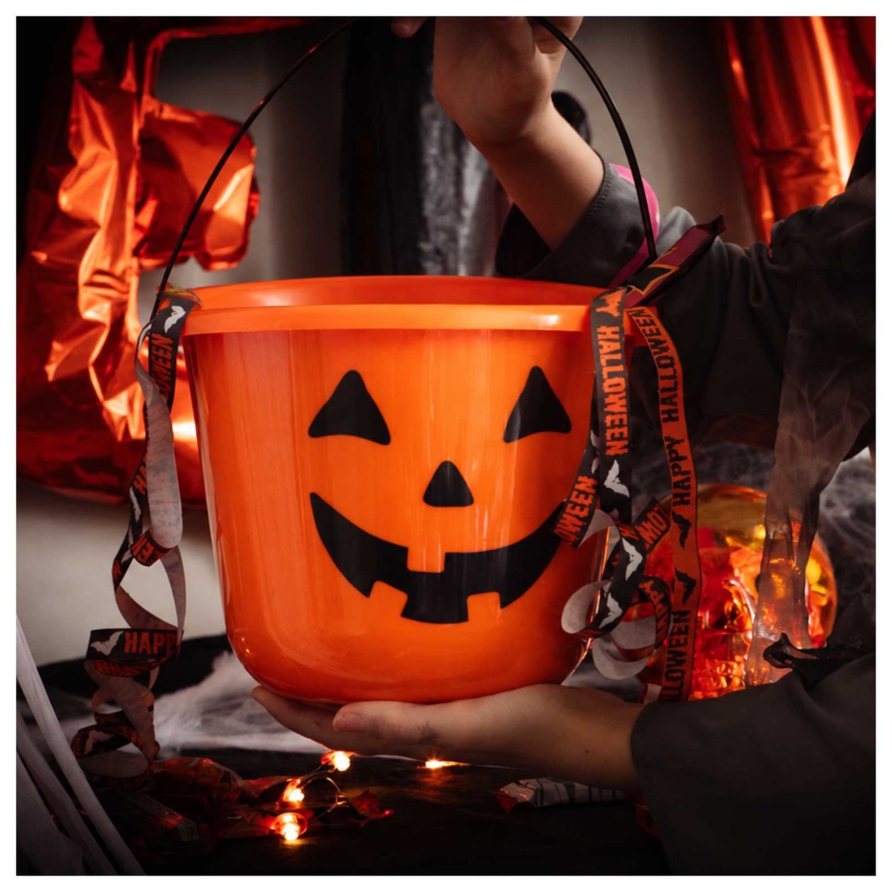 Oransje Halloween-bøtte med gresskarmotiv i Halloween-miljø.