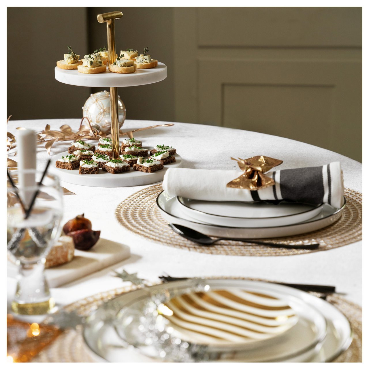 Elegante Neujahrstafel in Weiß und Gold mit Etagere und festlichen Häppchen.