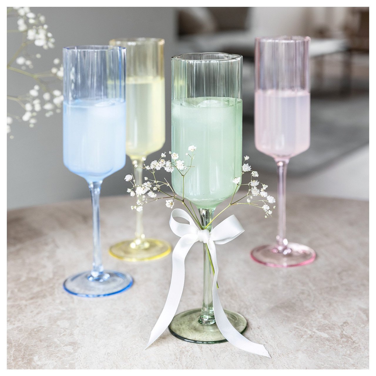 Fyra champagneglas i olika pastellfärger.