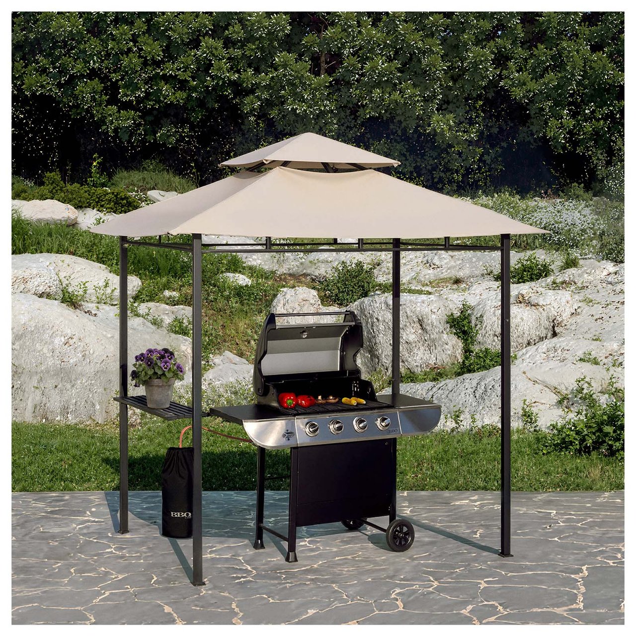 Gasgrill in einem Pavillon auf einer Terrasse mit Naturstein und Grün im Hintergrund.