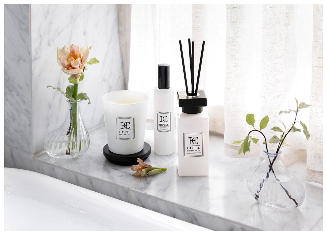 Duftkerzen und Duftstäbchen auf einer Fensterbank aus Marmor mit kleiner Vase mit Schnittblumen.