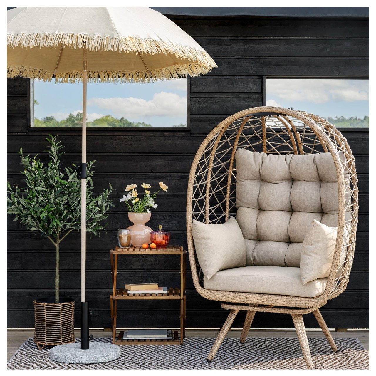 Eine gemütliche Ecke auf der Terrasse mit dem Entspannungsstuhl Capri, einem Beistelltisch und einem Sonnenschirm mit Fransen.