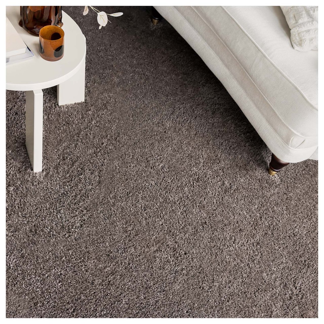 Brauner Teppich mit langem Flor unter einem weißen Sofa und einem weißen Tisch.