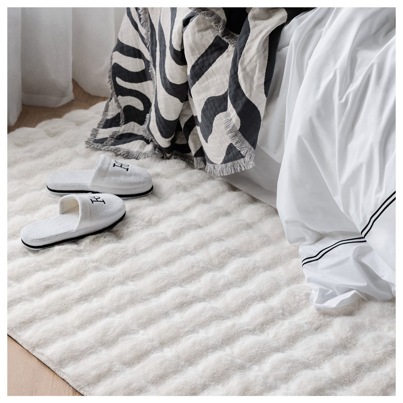Vit, fluffig matta sticker fram under säng.