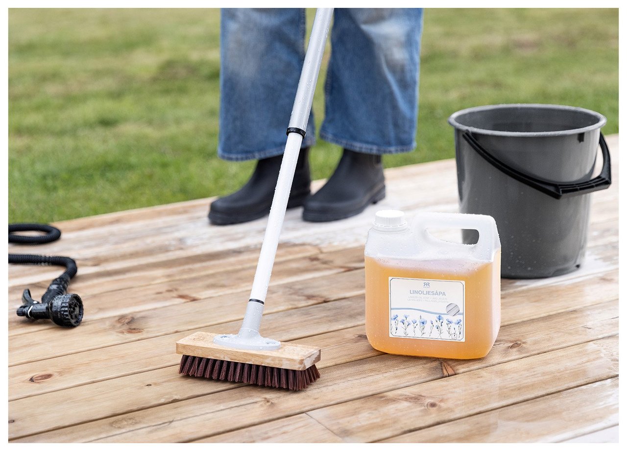 En person skurar en altan med linoljesåpa.