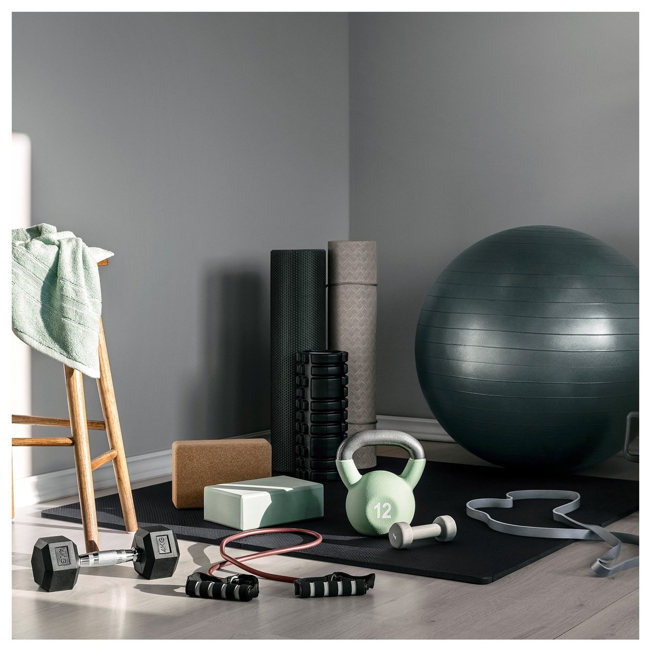Trainingsecke zu Hause mit Gymnastikball, Kettlebell, Yogamatte, Faszienrollen, Bändern und Trinkflaschen.