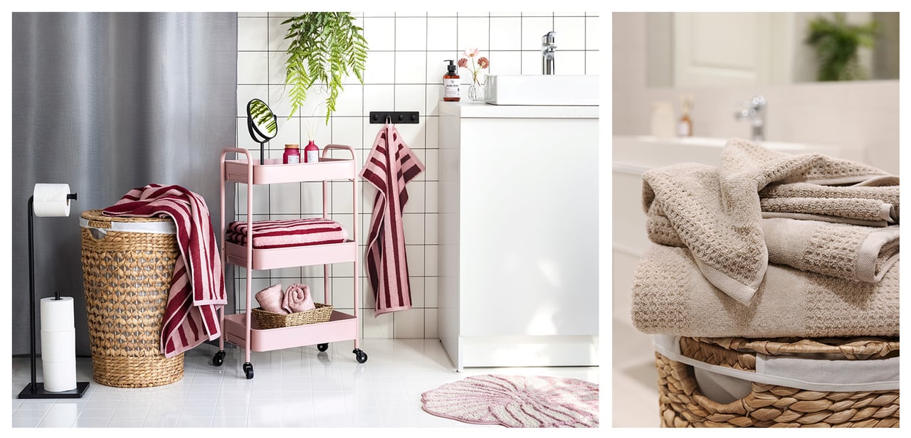 Weiß gefliestes Badezimmer mit rosa Rollwagen, Badematte und rosagestreiften Handtüchern. Wäschekorb mit beigefarbenen Handtüchern.