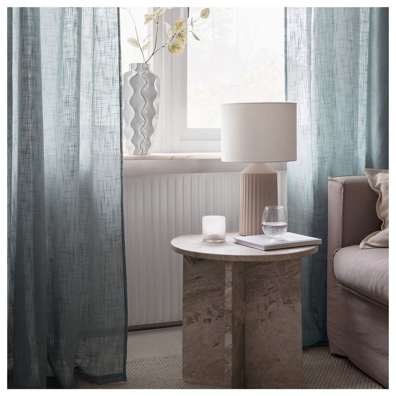 Wohnzimmer mit dünnen graugrünen Vorhängen.