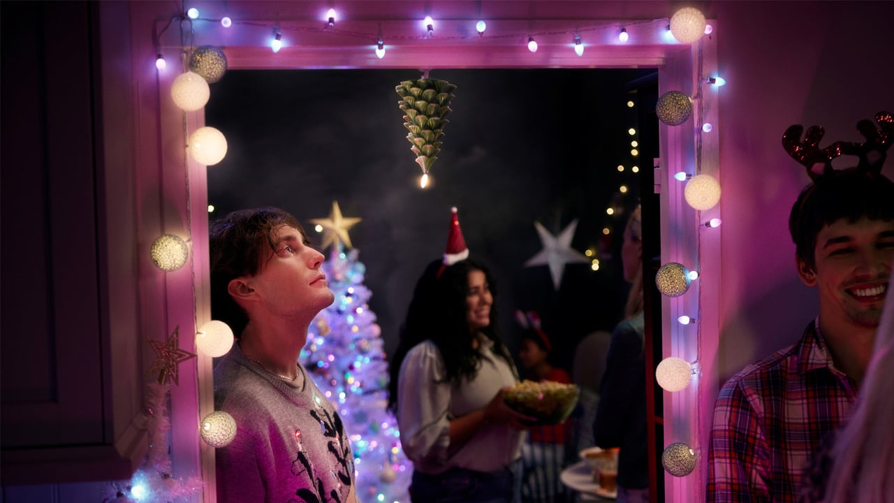 Ein Türrahmen ist mit einer Lichterkette geschmückt und beleuchtet den Raum mit Weihnachtsfeier im Hintergrund.