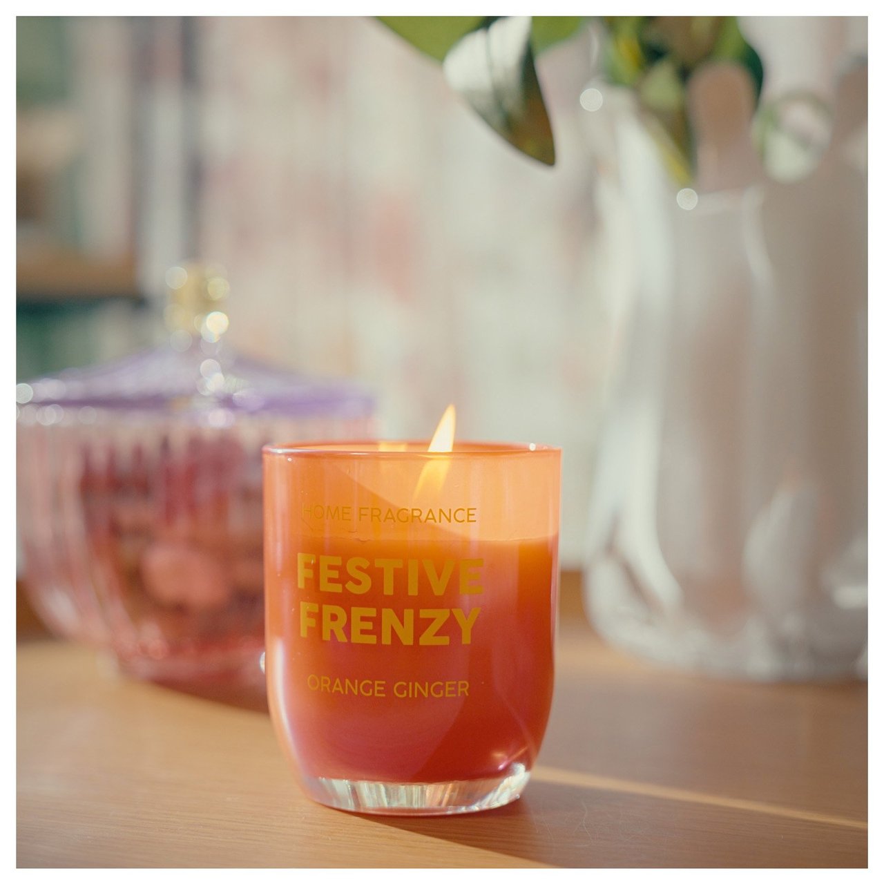 Palava tuoksukynttilä pöydällä yhdessä koriste-esineiden kanssa kodikkaassa ympäristössä.